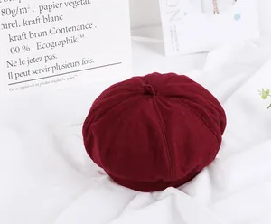 Close-up of a burgundy wool beret on white fabric with decorative card background