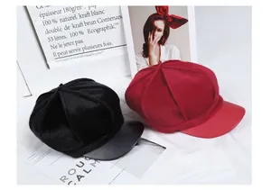 Detail of faux fur and matte leather visors on black and burgundy newsboy caps