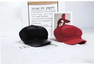 Detail of plush faux fur octagonal newsboy caps in black and burgundy with leather brims
