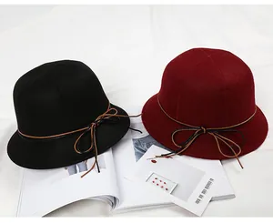 Detail of wool cloche hats in black and burgundy with delicate leather bow accents