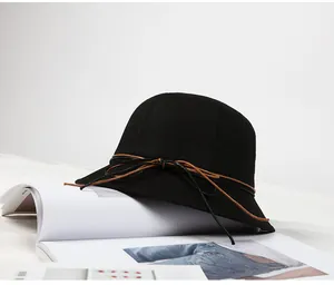 Close-up of a black wool felt bucket hat with a leather bow tie on a fashion magazine