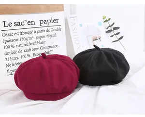 Flat lay of wool beret hats in burgundy and black with fashion magazine background