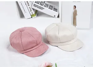 Detailed view of pink and beige suede newsboy caps with premium stitched texture