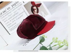 Detail view of burgundy faux fur newsboy cap with contrasting shiny red leather brim