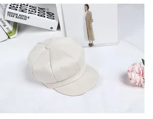 Detailed close-up of cream-white newsboy cap with soft textured fabric and stitched panels