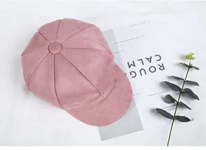 Top view of a pink suede newsboy cap featuring octagonal stitching and top button