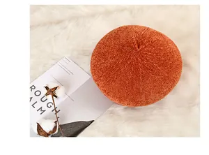 Detail view of orange knitted beret texture on soft white faux fur background