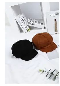 Detail view of stylish black and brown newsboy caps styled with fashion magazines