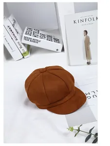 Detail of a brown suede newsboy cap with stitched panels and a top button decoration