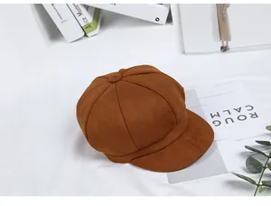 Brown faux suede octagonal newsboy hat styled with decorative books and greenery