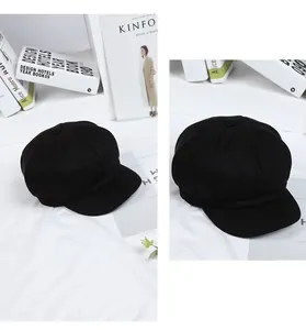Detailed view of a vintage black baker boy cap with textured fabric and top button