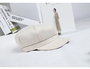 Detailed texture of a beige suede newsboy cap displayed on minimalist style magazines