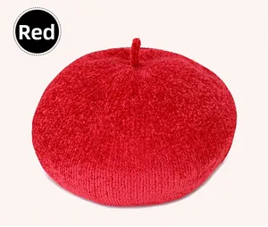 Detail of red knit beret featuring thick textured fabric and a decorative top stem