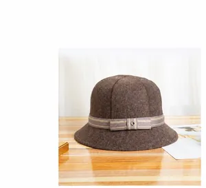 Dettaglio del cappello a secchiello in lana marrone con nastro a righe e occhiello in metallo