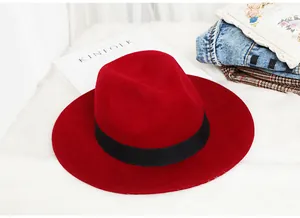 Top view of red wool fedora with black ribbon on a soft white faux fur background