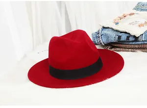 Detail of red wool fedora with black grosgrain ribbon on soft white fur background