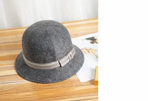 Dettaglio cappello a secchiello in lana grigia con nastro a righe e bottone metallico