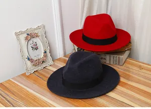 Classic red and navy wool fedora hats with black ribbons on a vintage wooden desk