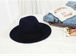 Close-up of wool fedora hat with wide brim and black ribbon on white fur rug