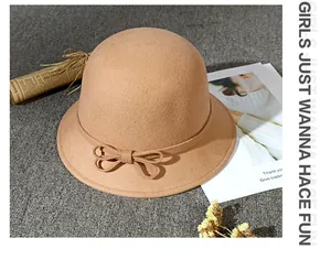 Detailed view of a camel wool felt fedora hat with a bow on grey textured fabric
