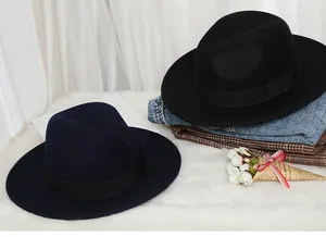 Detailed view of navy and black wool fedora hats with ribbon bands on soft rug