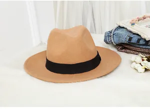 Close-up of camel wool fedora with black grosgrain ribbon on a soft faux fur surface