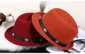 Detail von Wollhüten in Dunkelrot und Orange mit Lederbändern und Vintage-Nieten