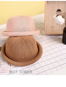 Detail of pink and brown straw sun hats with rolled edges on a white background