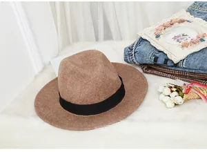 Detailed texture of brown wool fedora hat with black ribbon on a soft white rug