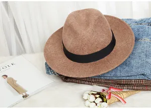 Detail of wool fedora hat with black ribbon on soft fur rug and stylish lifestyle backdrop