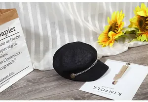 Dettaglio di un cappello newsboy nero intrecciato con nastro stampato NICE e bottone