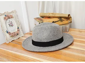 Close-up of grey wool fedora hat with black ribbon on a vintage wooden desk