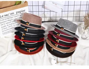 Detail van wollen fedora hoeden in diverse kleuren met een gouden bijen metalen gesp