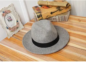 Top view of a vintage light gray wool fedora hat with a black ribbon on a wooden table