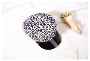 Dettaglio del cappello baker boy leopardato con visiera nera lucida su sfondo bianco