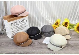 Dettaglio ravvicinato di cappelli newsboy in paglia intrecciata con nastro e bottone