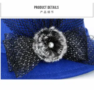Detail of royal blue felt hat with black mesh bow, soft fur pompom, and pearl accent