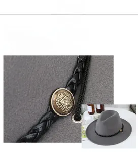 Detail of vintage metal crest buckle on braided leather band of a grey wool fedora hat