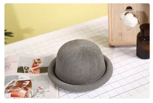 Detail shot of a grey mesh woven dome hat with a stylish rolled brim on a plaid table