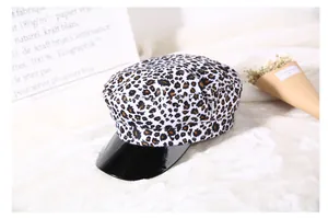 Dettaglio cappello marinaio leopardato con visiera nera lucida su fondo bianco morbido