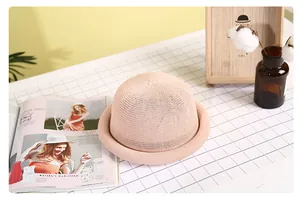 Detailed view of pink woven straw dome hat with a rolled brim on a rustic table