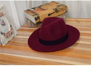Burgundy wool fedora hat with black ribbon on a wooden table with vintage books