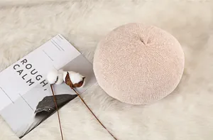 Close-up of the knitted texture and small top tail on the beige wool beret hat