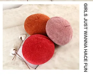 Flat lay of knit beret hats in red, pink, and orange on a soft plush background