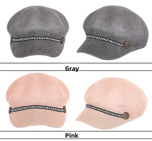 Dettaglio di berretti newsboy in mesh rosa e grigio con nastro a lettere e bottoni
