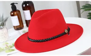 Detail of red wool fedora hat featuring a black woven leather belt and gold buckle