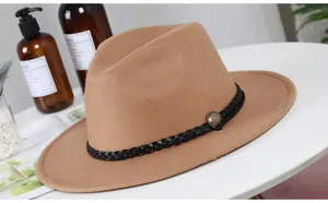 Close-up of camel wool fedora hat featuring a black woven band and antique metal buckle