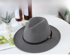 Detail of dark grey fedora hat featuring a woven black band and vintage copper button