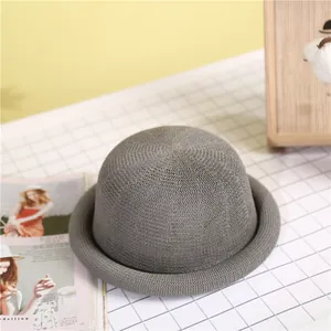 Elegant grey woven straw bowler hat with rounded brim on a minimalist studio set