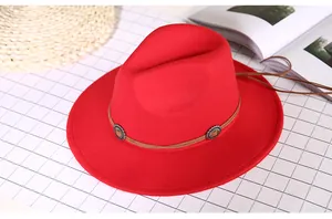 Detail of red wool felt fedora featuring a brown cord band and ethnic metal buckles